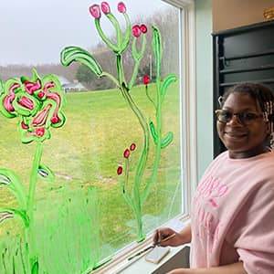 Student paining plants on a window