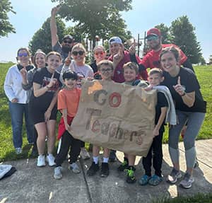 Adults and students holding a sign that reads Go Teachers